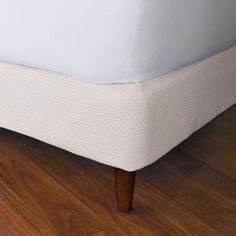 a close up view of a bed with white sheets and wooden legs on the floor