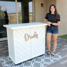 a woman standing in front of a white bar with the word drinker on it