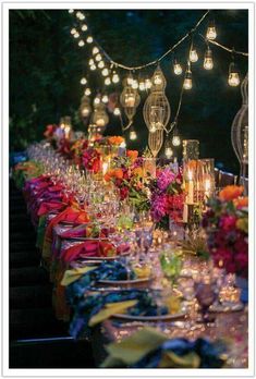 a long table covered in lots of glasses and plates with lit candles on top of them