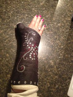 a woman's hand with pink nail polish and black knitted arm warmers