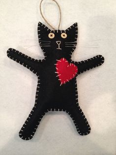 a black cat ornament with a red heart hanging from it's back