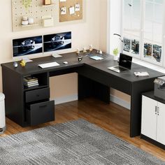 an office desk with two monitors on the wall and a file cabinet in front of it