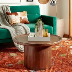 a living room with a green couch and coffee table in front of a colorful rug