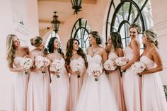 a group of women standing next to each other holding bouquets in front of a window