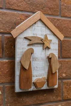 a wooden nativity scene on the side of a brick wall, with two people and a star