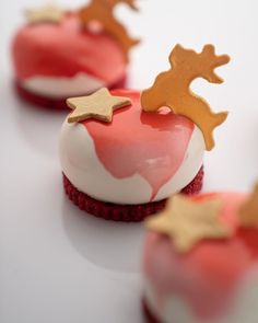 small red and white desserts with gold decorations on the top, sitting on a table