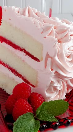 a close up of a cake with raspberries on the side and frosting