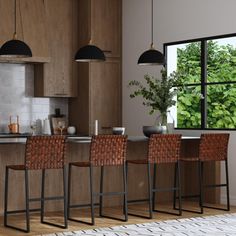 a kitchen with wooden cabinets and bar stools next to an open window that looks out onto the woods