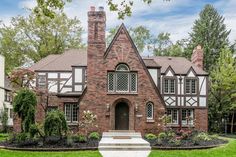 a large brick house with lots of windows and plants in front of the entrance to it