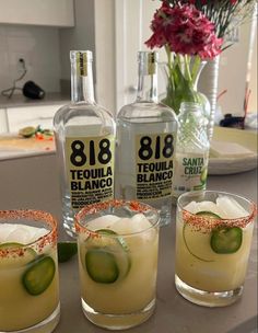 three glasses filled with drinks sitting on top of a counter