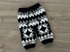 a pair of black and white crocheted leg warmers sitting on top of a wooden floor