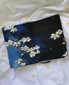 an open notebook sitting on top of a bed covered in white flowers