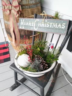 a wooden sign sitting on top of a chair next to a planter filled with pine cones