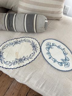 two blue and white plates sitting on top of a bed