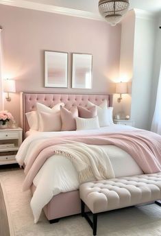 a bedroom with pink walls, white bedding and chandelier hanging from the ceiling