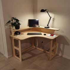 a corner desk with a computer on it and a potted plant in the corner