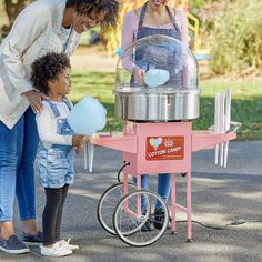 two women and a child are looking at an ice cream cart