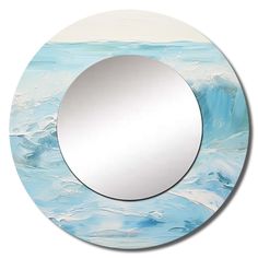 a round mirror sitting on top of a blue and white wall next to a body of water