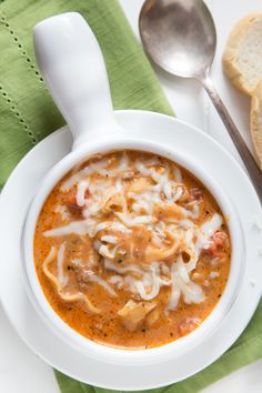 a white bowl filled with soup next to two slices of bread on top of a green napkin