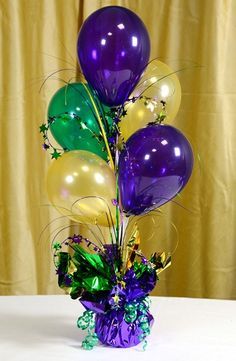 a vase filled with balloons and streamers on top of a table