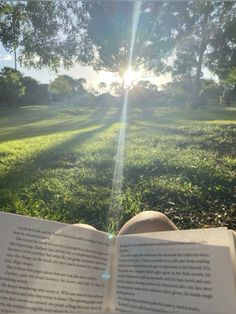 an open book sitting on top of a lush green field