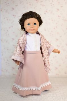 the doll is wearing a pink dress and coat