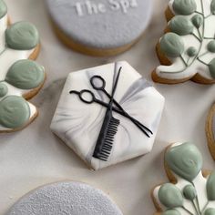 some decorated cookies with scissors and hair combs on top of each cookie, along with the words the spa