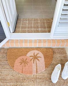 a pair of white shoes sitting on top of a door mat next to a doorway