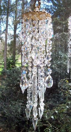 a crystal chandelier hanging from the ceiling in front of some trees and bushes