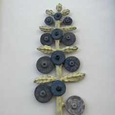 a wall hanging made out of clay and stoneware with blue buttons on it's sides