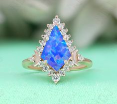 a ring with a blue opal surrounded by white and pink diamonds on a green surface