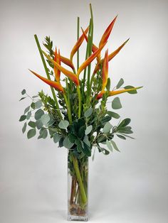 a vase filled with lots of green and orange flowers