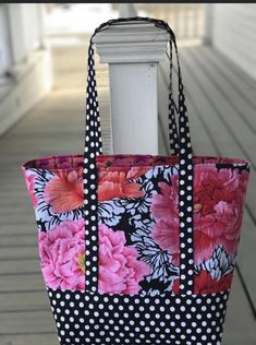 a black and white polka dot bag with pink flowers on the front, sitting on a porch