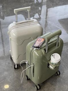 two pieces of luggage sitting next to each other on top of a tile floor with a cell phone hooked up to it