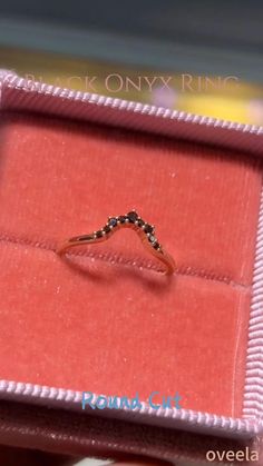 a ring is in a pink box on top of a red carpeted tablecloth