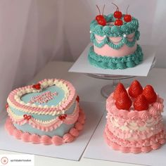 three cakes decorated in different colors and designs with strawberries on the top one cake is shaped like a heart