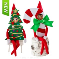 two elfs sitting next to each other on top of a piece of wood with ribbons