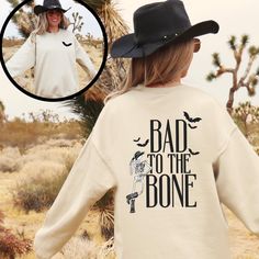 Saddle up for a spooky season with our trendy western Halloween "Bad to the Bone' sweatshirt. This sweatshirt features a cute halloween bat on the front and a cool cowboy skeleton leaning against the words printed on the back. Embrace your inner cowgirl and add a little western flair to your Halloween wardrobe. Whether you're heading to a fall festival or a Halloween hoedown, this shirt is perfect for you and all your ghoul friends! A sturdy and warm sweatshirt bound to keep you warm in the colder months. A pre-shrunk, classic fit sweater that's made with air-jet spun yarn for a soft feel and reduced pilling. * 50% cotton, 50% polyester * Pre-shrunk * Classic fit * 1x1 athletic rib knit collar with spandex * Air-jet spun yarn with a soft feel and reduced pilling * Double-needle stitched co Halloween Hoedown, Cowboy Skeleton, Skeleton Cowboy, Gifts For Halloween, Western Sweatshirts, Western Halloween, Cowboy Shirt, Cowgirl Shirts, To The Bone