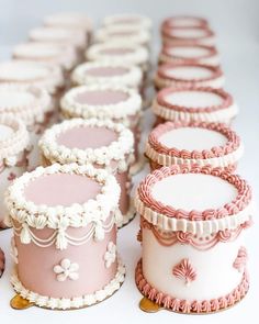 there are many pink and white cakes on the table