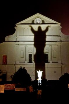 the shadow of a person standing in front of a building with a clock on it