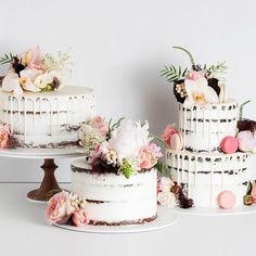 three tiered cakes with flowers on them sitting next to each other in front of a white wall