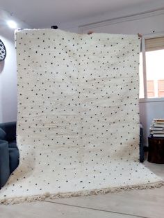 a living room with a large white rug on the floor next to a blue couch