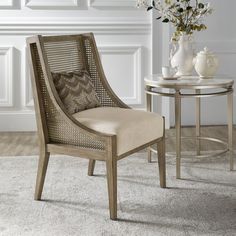 a chair sitting next to a table on top of a white carpeted floor in front of a vase with flowers