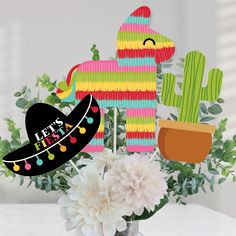 a vase filled with flowers and paper cutouts in the shape of cactuses, mexican hats, and sombrero