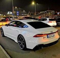 a white car parked in a parking lot next to other cars on the side of the road