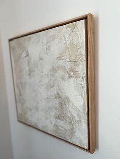 a painting is hanging on the wall next to a white wall with a wooden frame