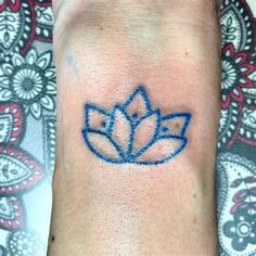 a small blue lotus tattoo on the wrist