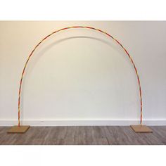 an arch made out of wood stands in front of a white wall and wooden floor