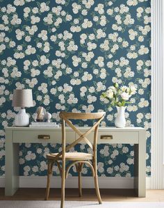 a chair and desk in front of a wallpapered with white flowers on it