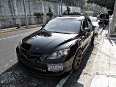 a black car is parked on the side of the road